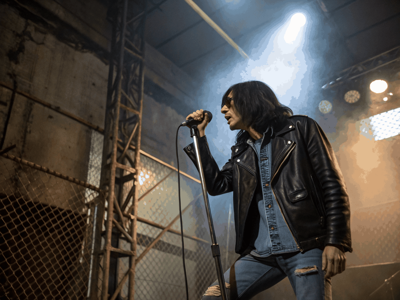 Hardcore vocalist gripping cable under harsh stage flash